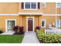 Inviting condo entrance featuring a red door and lush landscaping at 2280 San Vital Dr # 101, Kissimmee, FL 34741
