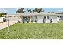 Charming single-story home with a well-manicured lawn, light gray brick, and a welcoming blue door at 2926 Carriage Dr, South Daytona, FL 32119