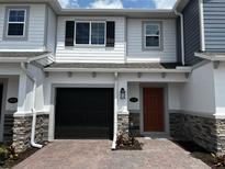 Charming townhome with a brick driveway, black garage door, and a welcoming orange front door at 5101 Prairie Preserve Run, St Cloud, FL 34772