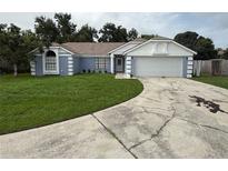 Charming single-story home featuring blue exterior paint, attached garage, and well-manicured lawn at 6026 Canyon De Chelley Ct, Orlando, FL 32810