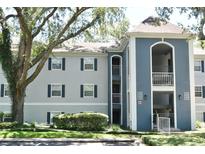 Multi-Gathering condo building with blue and gray facade, balcony, and lush, mature landscaping at 7104 Olympia Ct # 7104, Longwood, FL 32779