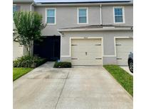 Charming two-story townhome with attached garage, landscaped yard and inviting entrance at 9033 Alba Ln, Kissimmee, FL 34747