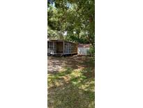 Exterior view of a home with a shed surrounded by trees and a yard at 9809 7Th Ave, Orlando, FL 32824