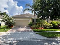 Charming home featuring a brick driveway and well-maintained landscaping, including palm trees and flowering bushes at 12728 Boggy Pointe Dr, Orlando, FL 32824