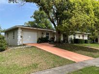 Charming one story home featuring a two-car garage, lush landscaping, and mature trees at 1310 Briarwood Ave, Deltona, FL 32725