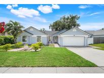 Charming single-story home with well-manicured lawn, lush landscaping and a two-car garage at 1322 Ravida Woods Dr, Apopka, FL 32703