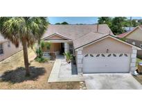 Charming single-story home featuring a two-car garage, covered porch, and lush landscaping at 1614 Oak Hill Trl, Kissimmee, FL 34747