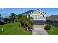 Two-story home with well-manicured lawn, front yard landscaping, and a two-car garage at 2530 The Oaks Blvd, Kissimmee, FL 34746