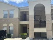 A multi-level exterior view of a condominium building with beige stucco and dark trim at 2770 Club Cortile Cir # A, Kissimmee, FL 34746