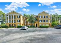 Three story tan condo building with black shutters, white columns, and landscaping in a parking lot at 3757 Conroy Rd # 2525, Orlando, FL 32839