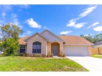 Charming single-story home with a brick facade, arched entryway, manicured lawn, and attached two car garage at 2444 Omaha Dr, Deltona, FL 32738