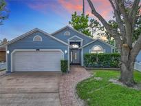 Charming blue single-story home featuring a well-manicured lawn, brick walkway, and attached two-car garage at 2641 Delcrest Dr, Orlando, FL 32817
