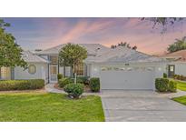 Charming single-story home with a well-manicured lawn and beautiful landscaping, featuring a two-car garage at 26908 Honeymoon Ave, Leesburg, FL 34748