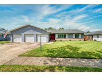 Charming single-story home with a well-manicured lawn, three-car garage and a vibrant red front door at 3024 Saratoga Dr, Orlando, FL 32806