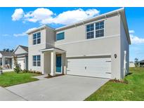 Charming two-story home featuring a two-car garage, blue door, and well-maintained landscaping at 5135 Marshelder St, Apopka, FL 32712