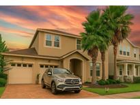 Charming two-story home with palm trees, a brick driveway, and a two-car garage against a colorful sunset backdrop at 5169 Dove Tree, Orlando, FL 32811