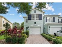 Inviting two-story townhome with a brick driveway, attached garage, and lush landscaping at 6027 Strada Isle Way, Orlando, FL 32835
