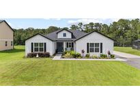 Charming single-story farmhouse with green lawn, blue door, black shutters and manicured landscaping at 7191 Old Melbourne Hwy, St Cloud, FL 34771