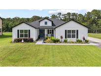 Charming two-story home with a beautifully landscaped yard, a blue door and dark shutters at 7191 Old Melbourne Hwy, St Cloud, FL 34771