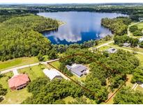 Aerial view of the property showcasing its proximity to a beautiful lake and surrounded by lush greenery and trees at 9642 Florida Boys Ranch Rd, Clermont, FL 34711