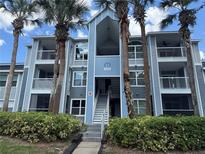 Inviting condo exterior features a light blue facade, multiple balconies, tropical palms, and lush greenery at 2592 Grassy Point Dr # 106, Lake Mary, FL 32746
