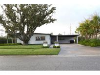 Charming single-story home with mature tree, carport, well-manicured lawn and lush landscaping at 319 Halsey St, Orlando, FL 32839