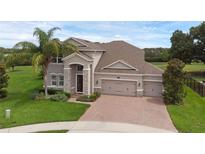 Charming home featuring a three-car garage, brick driveway, beautiful landscaping, and a lovely front yard at 32004 Redtail Reserve Blvd, Sorrento, FL 32776