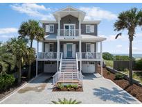 Gray two-story home with double balconies, a beach view, and a two-car garage at 3309 Hill St, New Smyrna Beach, FL 32169