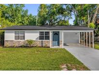 Charming home featuring stone accents, a blue front door, and a well-manicured lawn at 461 Brentwood Dr, Daytona Beach, FL 32117