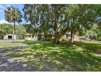Charming home featuring a stone facade, mature trees, and a lush, green lawn at 546 Winona Dr, Geneva, FL 32732