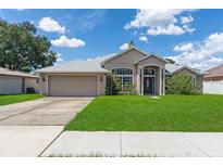 Charming single-story home featuring a manicured lawn, arched entryway, and an attached two-car garage at 1154 Feather Dr, Deltona, FL 32725