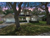 Charming two-story home featuring a well-manicured lawn, mature trees, and an attached two-car garage at 1225 Hollow Pine Dr, Oviedo, FL 32765