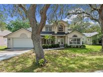 Charming home featuring a well-maintained lawn, mature trees, and a two-car garage, complete with inviting curb appeal at 1225 Hollow Pine Dr, Oviedo, FL 32765