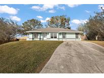 Charming single-story home featuring a well-manicured lawn and a concrete driveway on a sunny day at 12419 Eryn Ct, Clermont, FL 34711