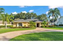 Charming single-story home featuring a circular brick driveway and lush, tropical landscaping at 1455 Royal Forest Loop, Lakeland, FL 33811