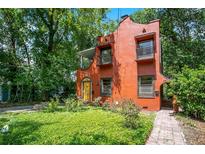 Charming two-story red home featuring a yellow door, two balconies, and lush landscaping at 1600 Dauphin Ln, Orlando, FL 32803