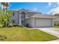 Charming two-story home with a well-manicured lawn and a two car garage on a sunny day at 16243 Wilkinson Dr, Clermont, FL 34714