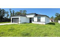 A modern single-Gathering home with a white exterior, gray accents, and a well-manicured lawn at 16252 Sw 27Th Terrace Rd, Ocala, FL 34473
