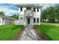 Charming two-story home with a modern white exterior, a welcoming walkway and lush green lawn at 2300 S Brown Ave, Orlando, FL 32806