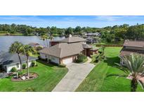 Expansive lakefront home with manicured lawn, mature palms, and a long driveway leading to an attached garage at 3604 Shell Cove Ln, Orlando, FL 32817