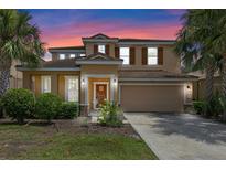Charming two-story home featuring a well-maintained lawn, a two-car garage, and beautiful palm trees at 5172 Oakbourne Ave, Davenport, FL 33837
