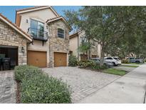 Charming townhome featuring a stone facade, private balcony, and a paver driveway leading to a two-car garage at 10423 Belfry Cir, Orlando, FL 32832