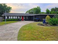 Charming home with a red front door, dark exterior, and well-maintained lawn at 1902 Sarazen Dr, Orlando, FL 32808