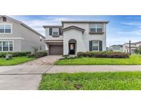 Two-story home with a well-manicured lawn, brick driveway, and stucco exterior at 2114 Fleming Mist Pl, Kissimmee, FL 34747