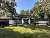 Charming home featuring well-manicured lawn, columns, neutral paint, and elegant arched windows at 2313 Park Village Pl, Apopka, FL 32712