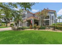 Charming two-story home with a well-manicured lawn, blossoming trees, and a gray exterior at 2388 Baronsmede Ct, Winter Garden, FL 34787