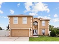 Two-story home featuring a two-car garage, neutral stucco, manicured lawn and white trim at 2725 White Magnolia Loop, Clermont, FL 34711