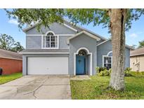 Charming two-story home with a two-car garage, blue door, and well-maintained lawn at 38 Jett Loop, Apopka, FL 32712