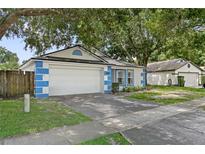 Charming one-story home featuring blue and white accents, a two-car garage, and mature landscaping at 4398 Fox Hollow Cir, Casselberry, FL 32707