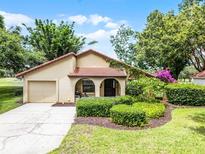 Charming single-story home featuring a red tile roof and a well-manicured front yard with lush landscaping at 6301 Parson Brown Dr, Orlando, FL 32819